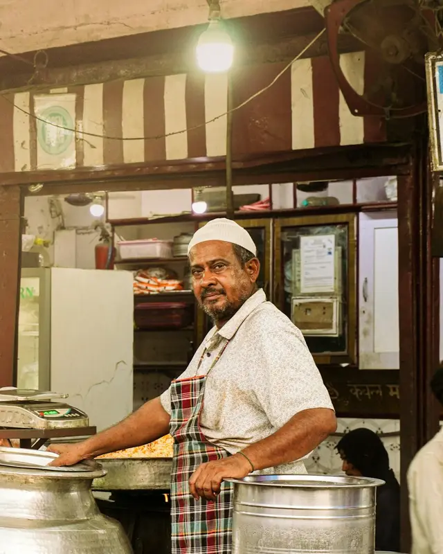 A smiling cook in an apron at a food stall