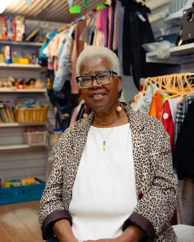 A smiling shop owner among racks of clothes